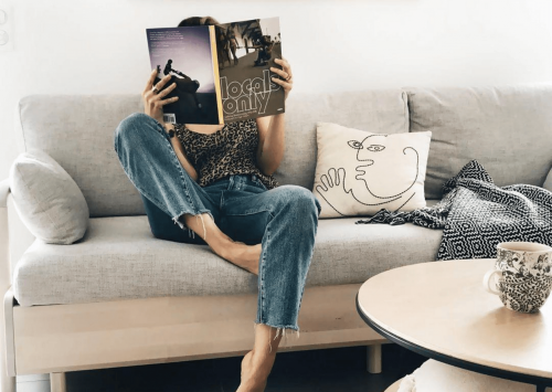 Jeune femme assise sur son canapé-lit en train de lire